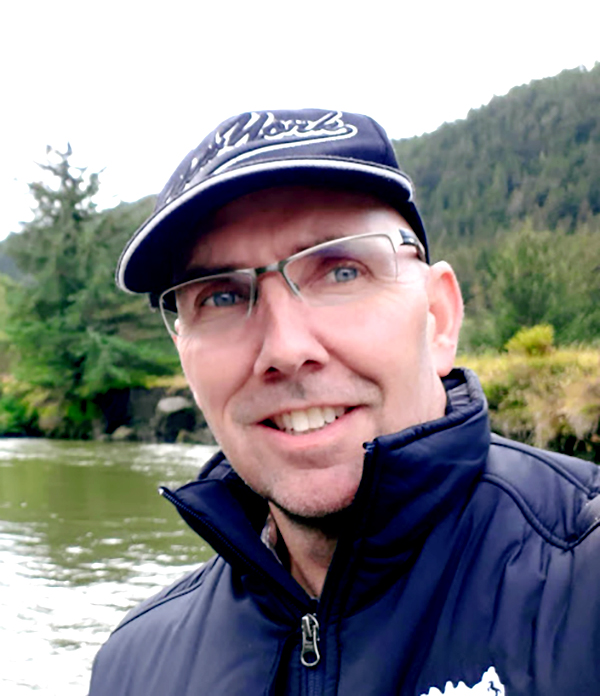 Mike Reimer poses in front of a river in the mountains.